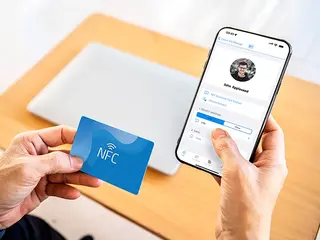 Two iPhones exchanging contact info next to an NFC business card
